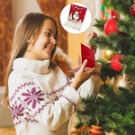 Girl holding red paper 3D Christmas cards with pop-up snowman at tree